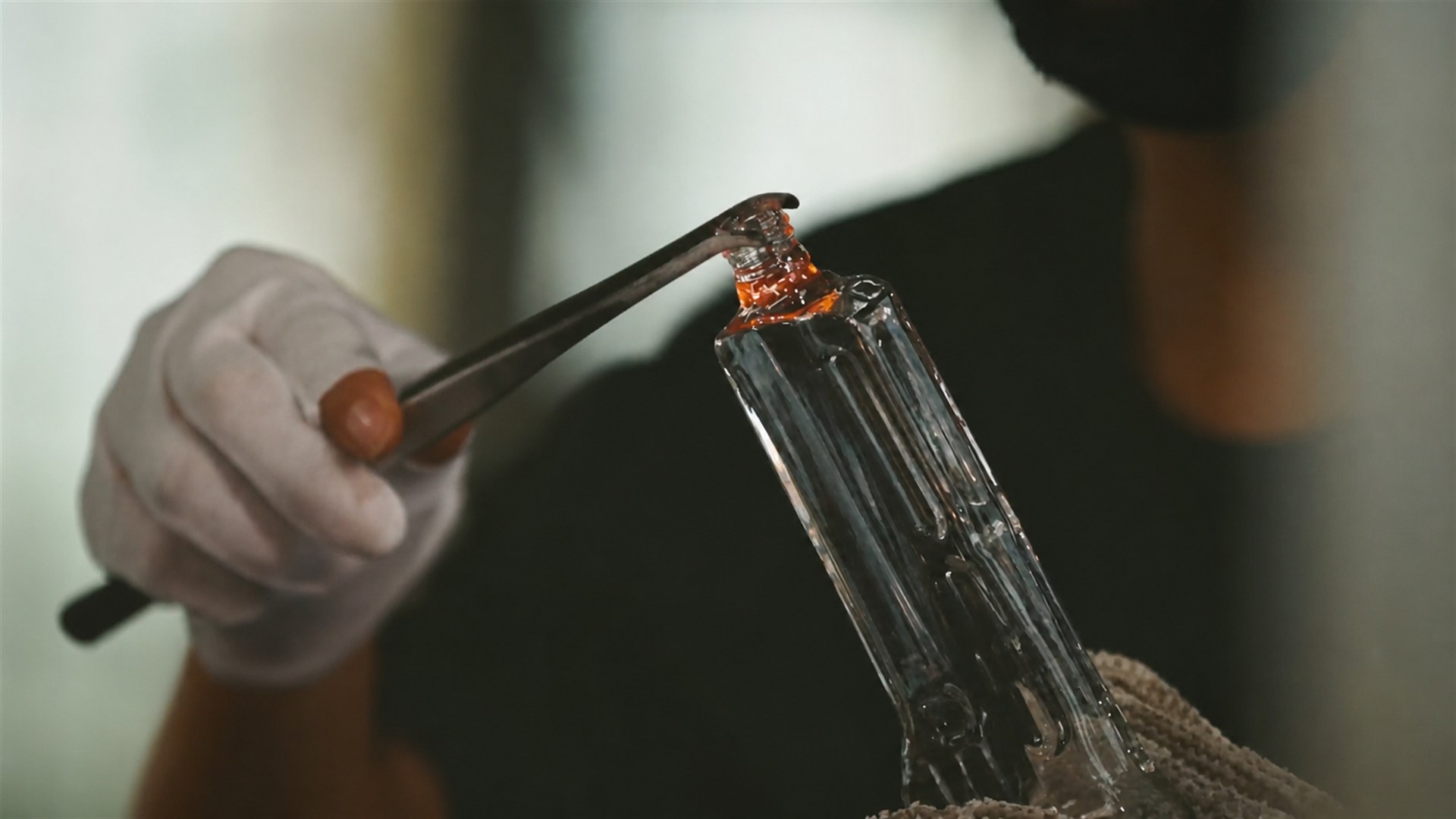 Craftsperson inspecting a hand-finished borosilicate glass component